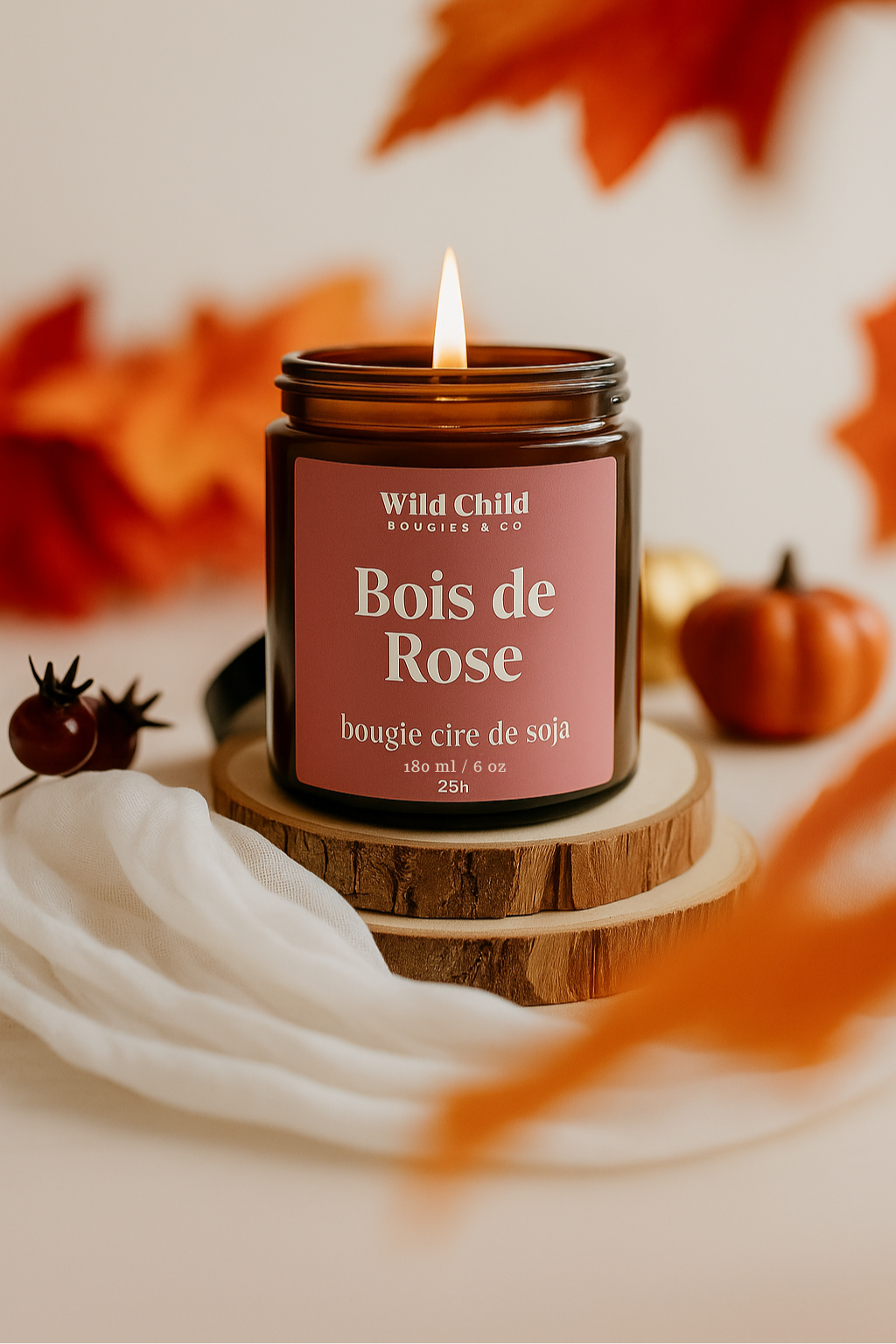 Bougie Bois de Rose allumée, en pot ambré, posée sur un rondin de bois avec décor automnal et ambiance chaleureuse.