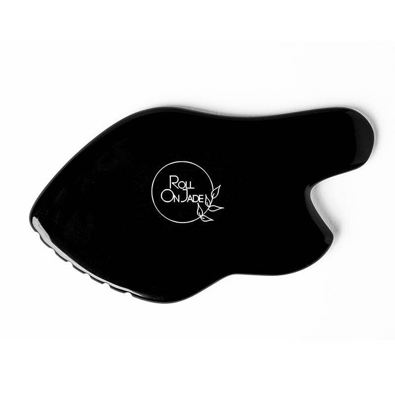 Gros plan du Gua Sha Ultimate Lift en Obsidienne Noire posé sur fond clair, mettant en valeur ses courbes sculptantes.