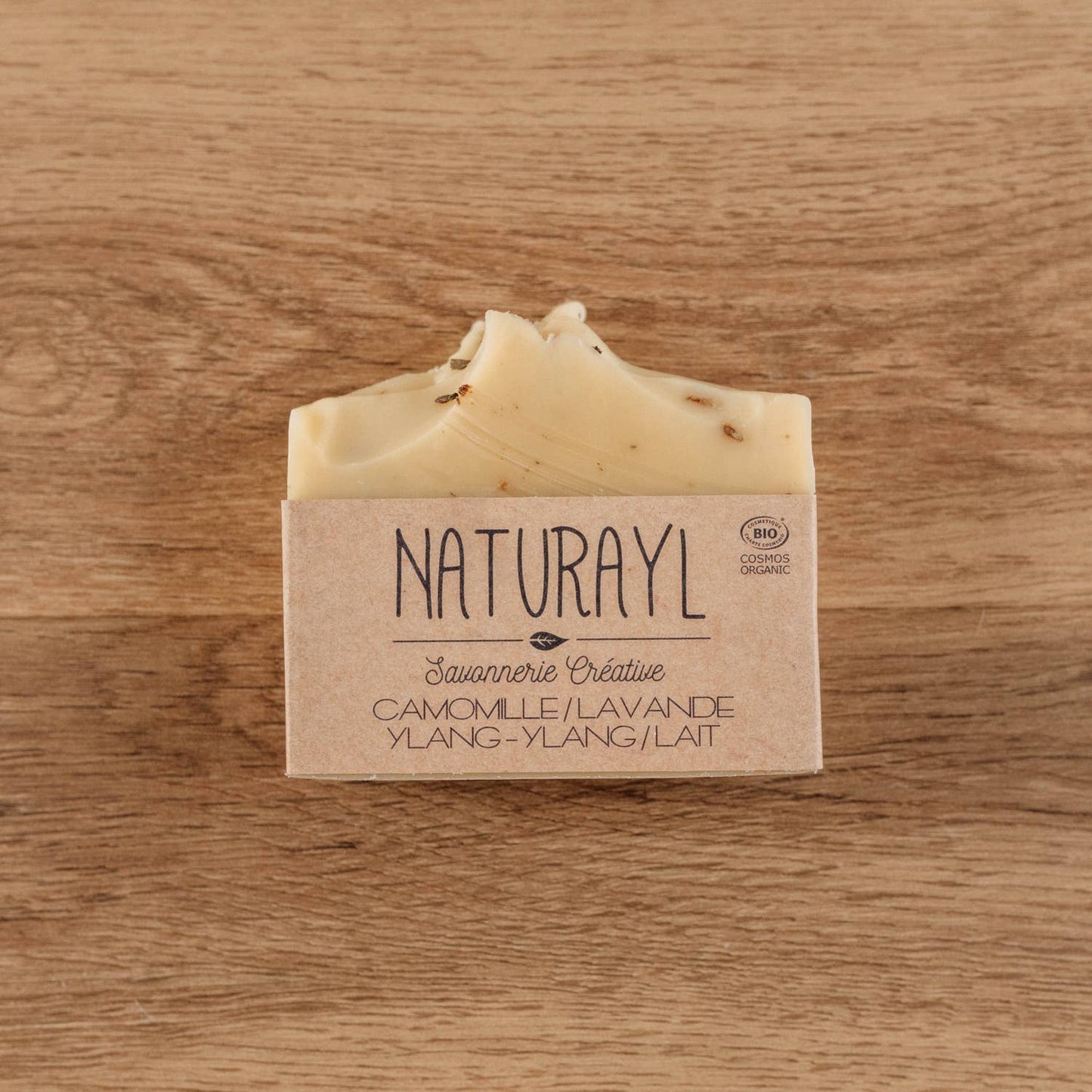 Photo du savon Naturayl posé sur une planche bois, avec étiquette “Camomille Lavande Ylang-Ylang Lait”.
