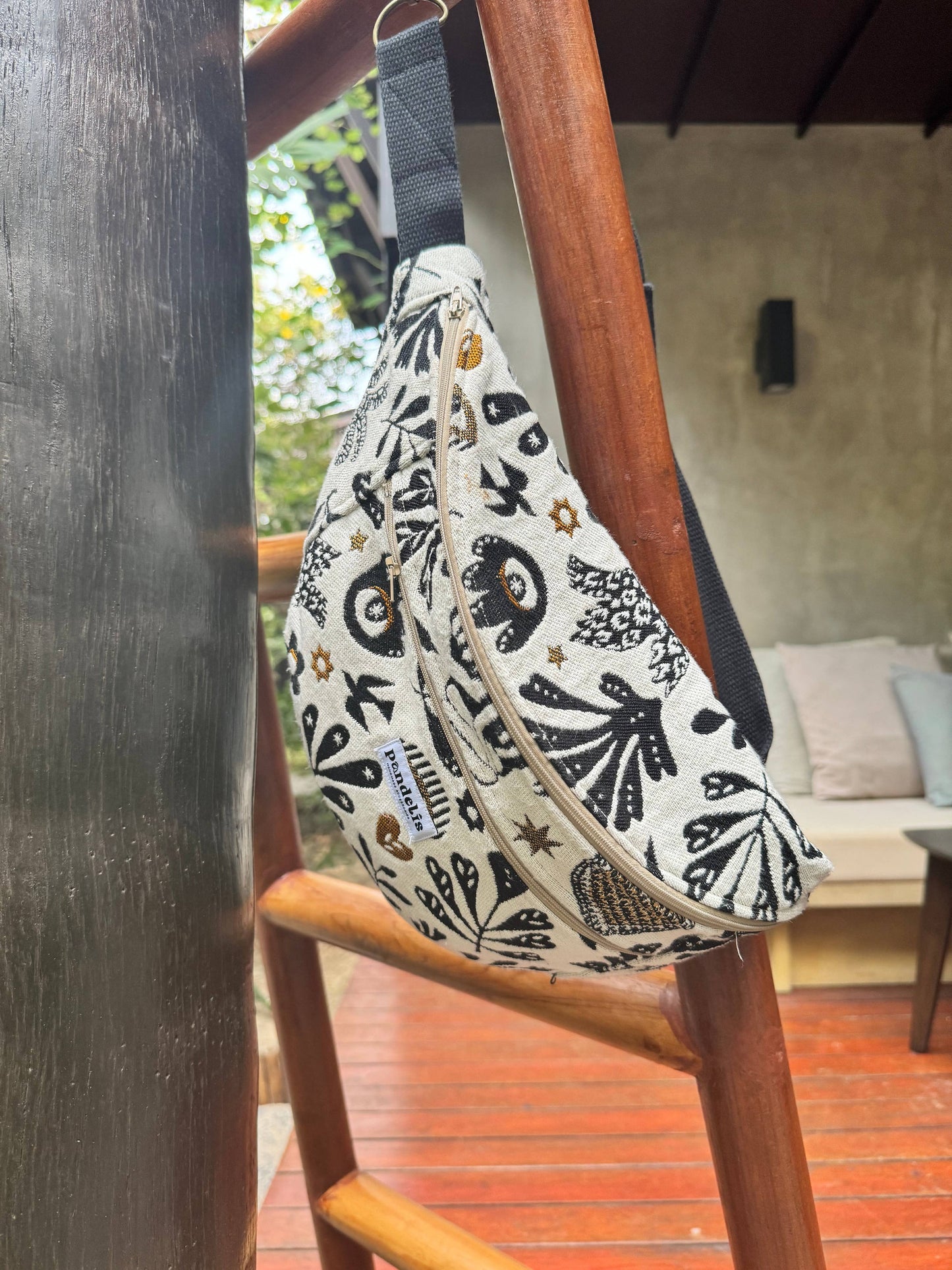 Détail de la grande banane Anthea en tissu écru et noir, accrochée verticalement à une poutre en bois