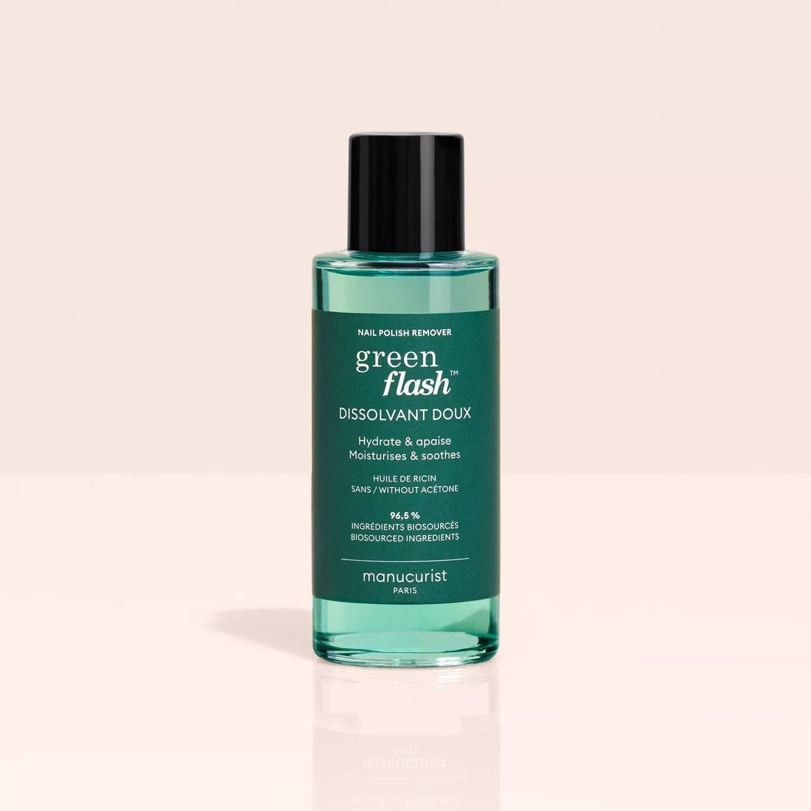 Flacon de dissolvant doux Green Flash™ Manucurist posé debout sur fond beige, mettant en valeur son packaging vert avec bouchon noir.