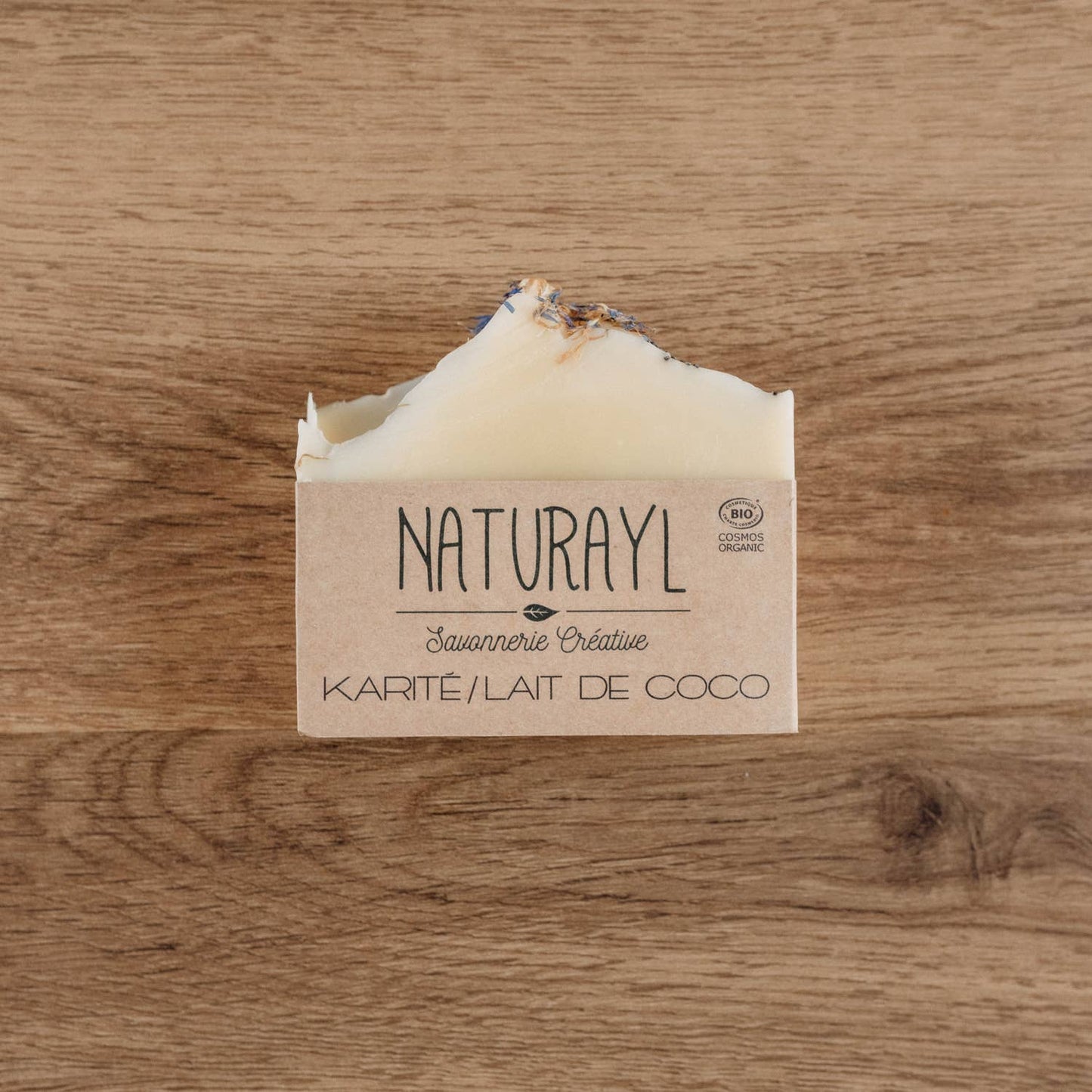 Savon Naturayl Karité Lait de Coco posé sur une table en bois, emballé dans son packaging kraft naturel.