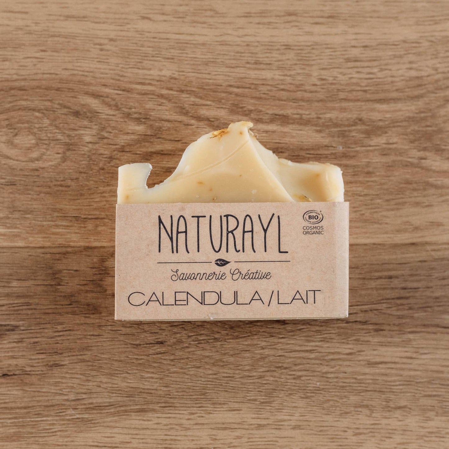 Savon artisanal Calendula & Lait Naturayl présenté sur un fond en bois naturel, fabriqué à la main selon la méthode de saponification à froid pour nettoyer la peau tout en douceur.