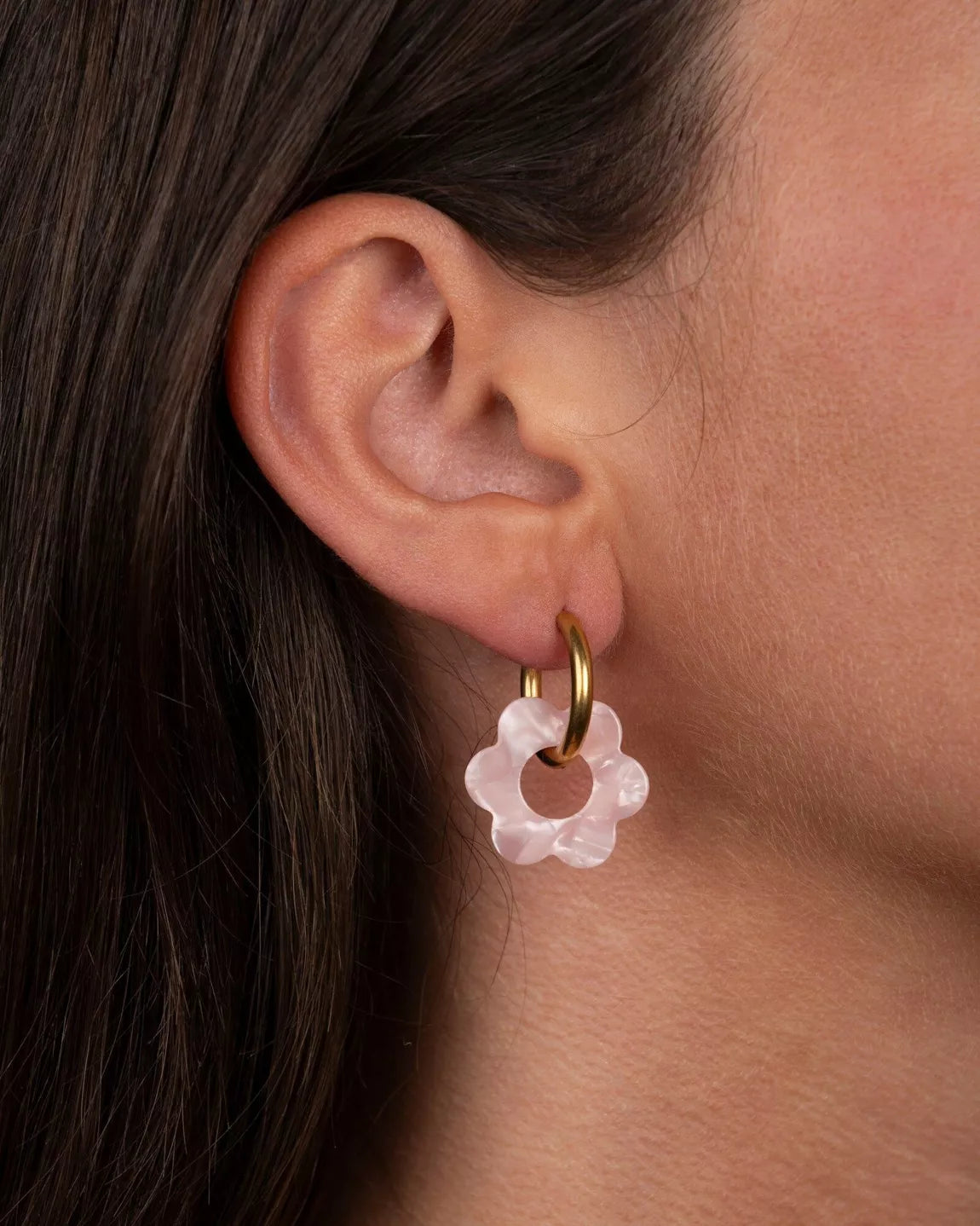 Boucles d’oreilles Baby Fleurette rose de Kurage portées à l’oreille, petites créoles dorées avec fleurs en acétate rose nacré.
