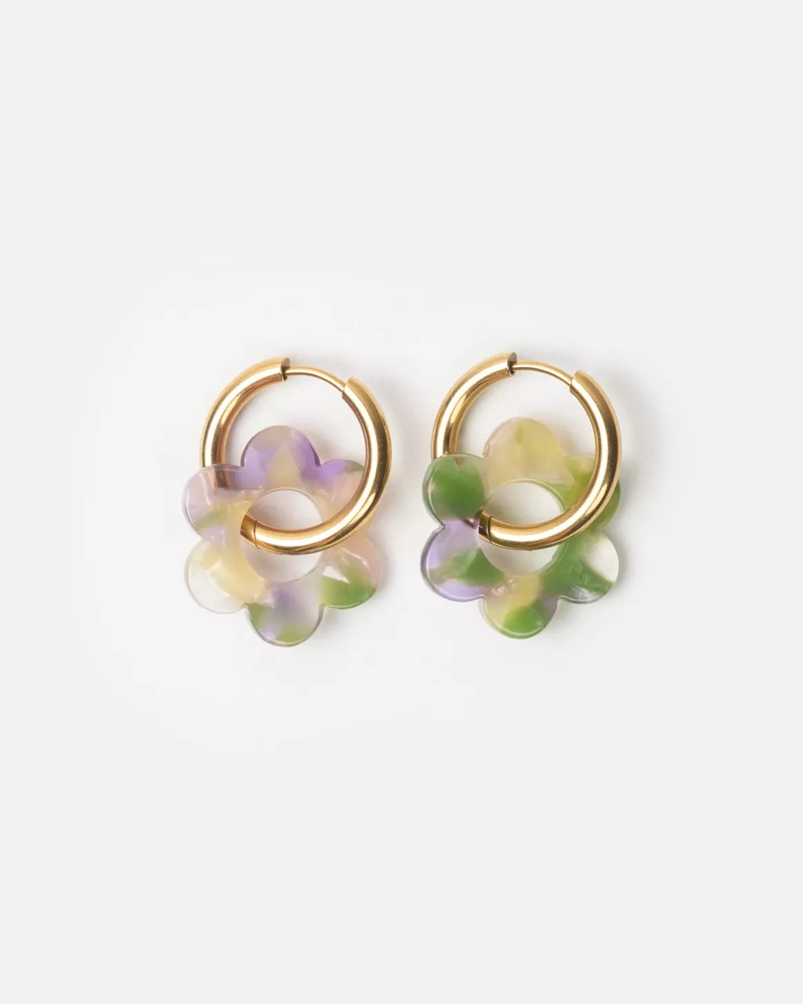 Paire de boucles d’oreilles Baby Fleurette lilas et vert de Kurage, créoles dorées ornées de pendentifs en forme de fleur en acétate marbré lilas, vert et ivoire, sur fond clair.