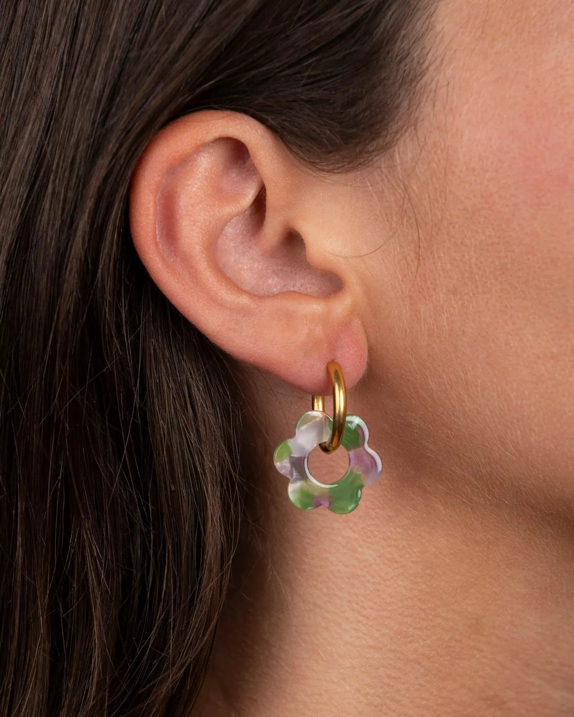 Boucles d’oreilles Baby Fleurette lilas et vert de Kurage portées à l’oreille, petites créoles dorées avec fleurs en acétate marbré lilas et vert.