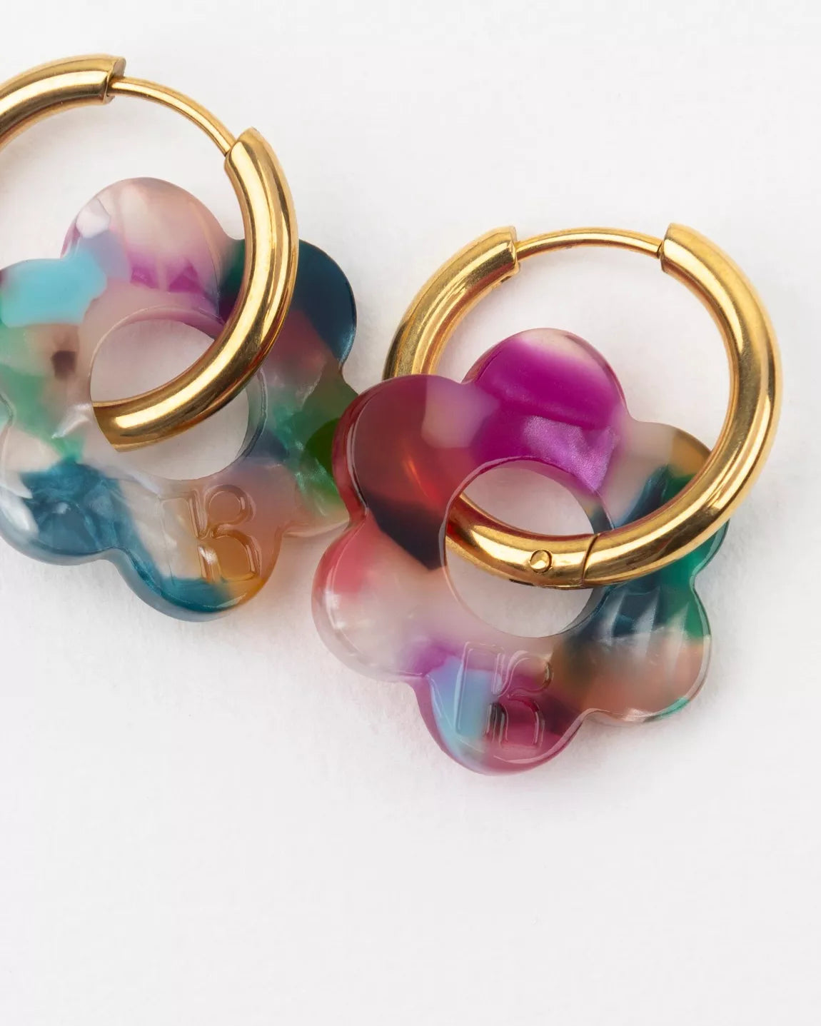 Détail des boucles d’oreilles BABY FLEURETTE Kurage Ginza, fleurs en acétate multicolore effet translucide gravées du logo K, avec anneaux dorés en acier inoxydable.