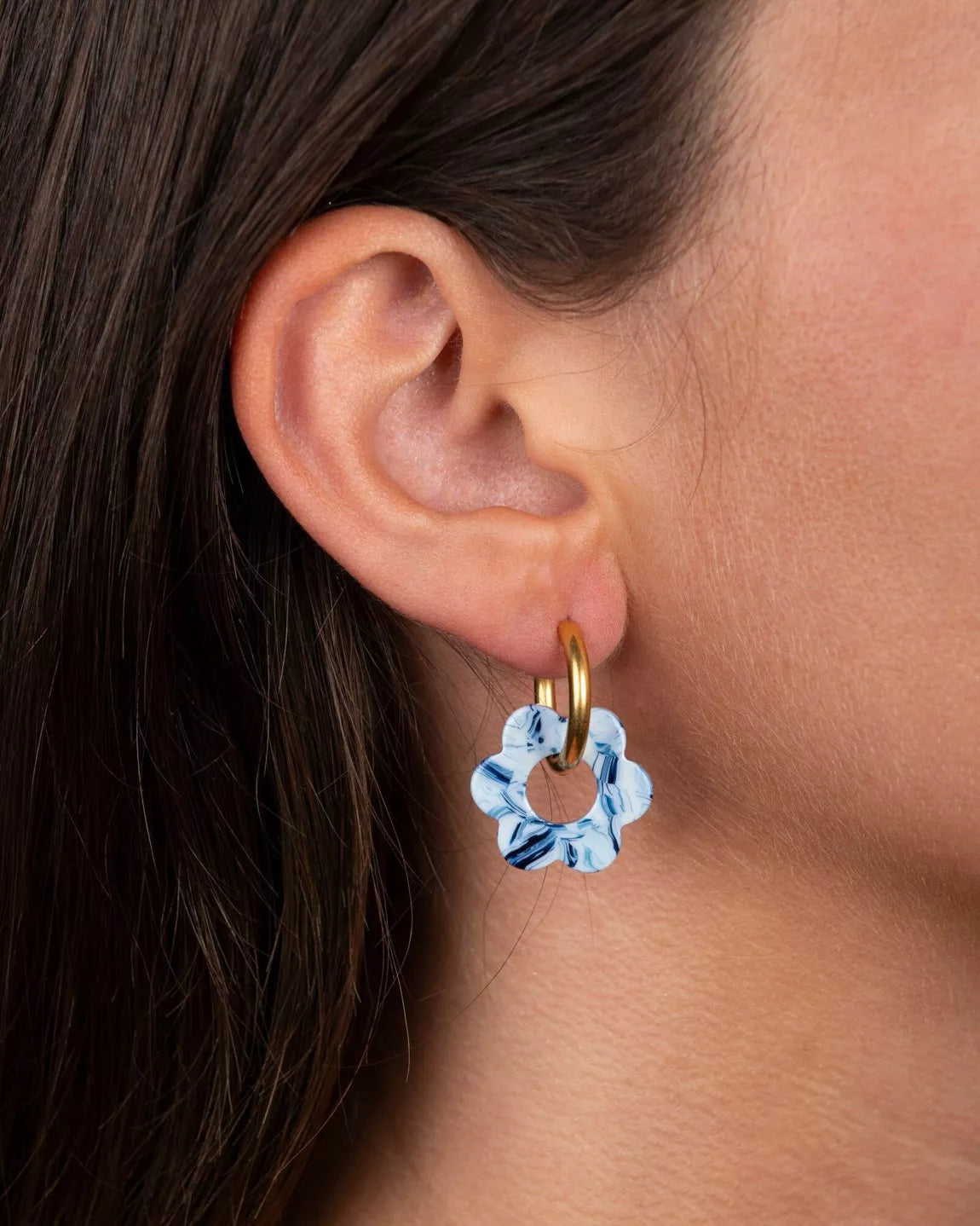 Boucle d’oreille BABY FLEURETTE Kurage Ginza portée à l’oreille, fleur bleu marbré sur anneau doré, bijou léger et coloré fabriqué en France.