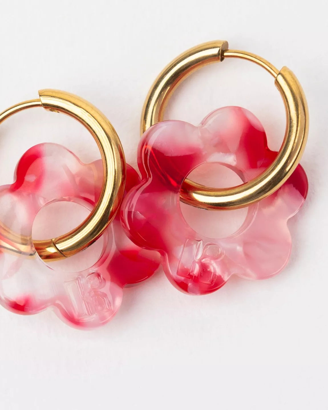 Détail des boucles d’oreilles Baby Fleurette rouge de Kurage, fleurs en acétate effet marbré rouge et rose sur anneaux dorés.