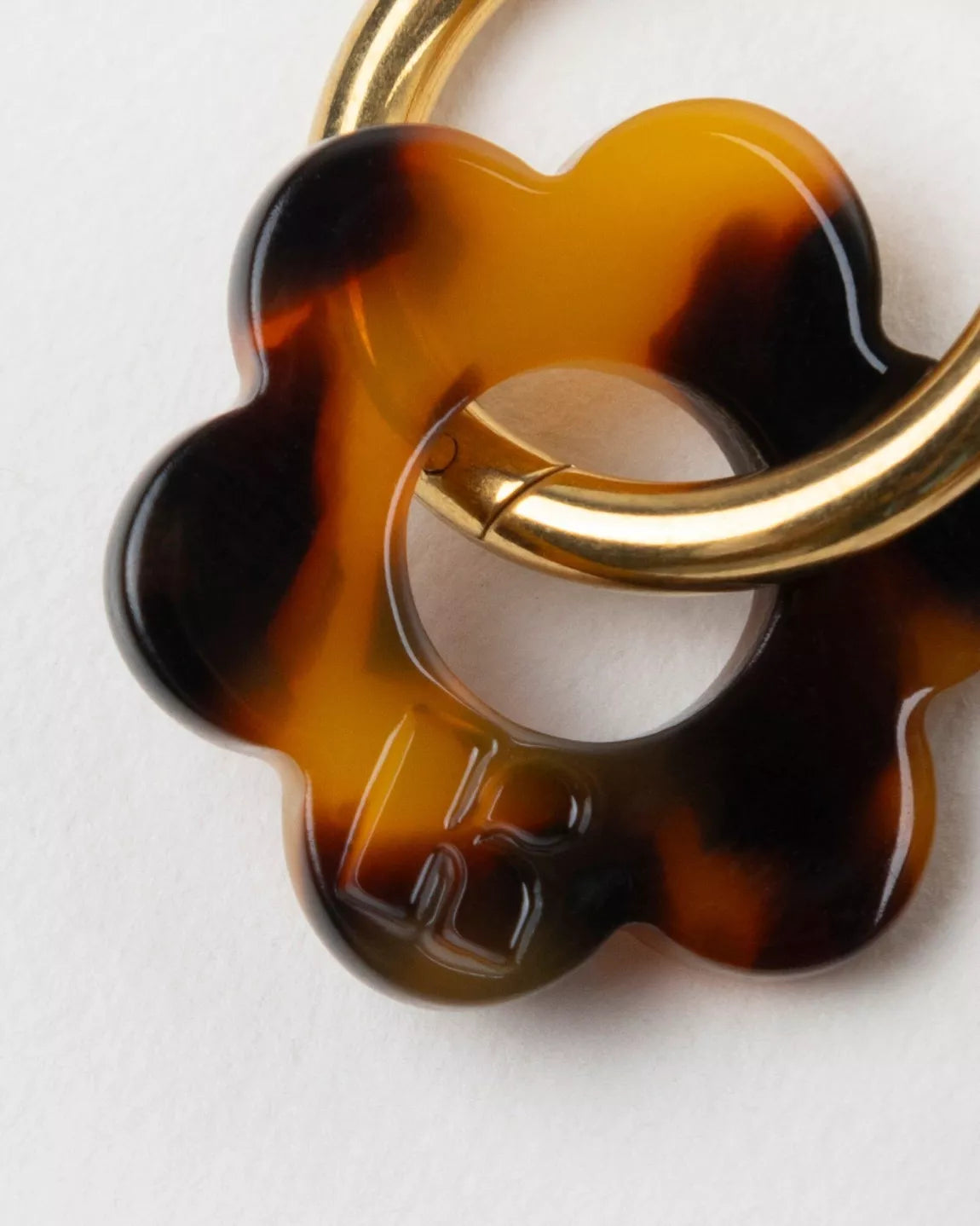 Détail des boucles d’oreilles BABY FLEURETTE Kurage Ginza, fleurs en acétate effet écaille de tortue avec anneaux dorés et logo K gravé.