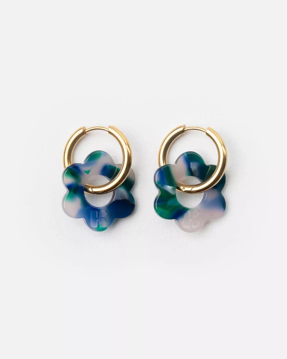 Paire de boucles d’oreilles Baby Fleurette bleu de Kurage, créoles dorées avec pendentifs en forme de fleur en acétate marbré bleu et vert, présentées sur fond clair.