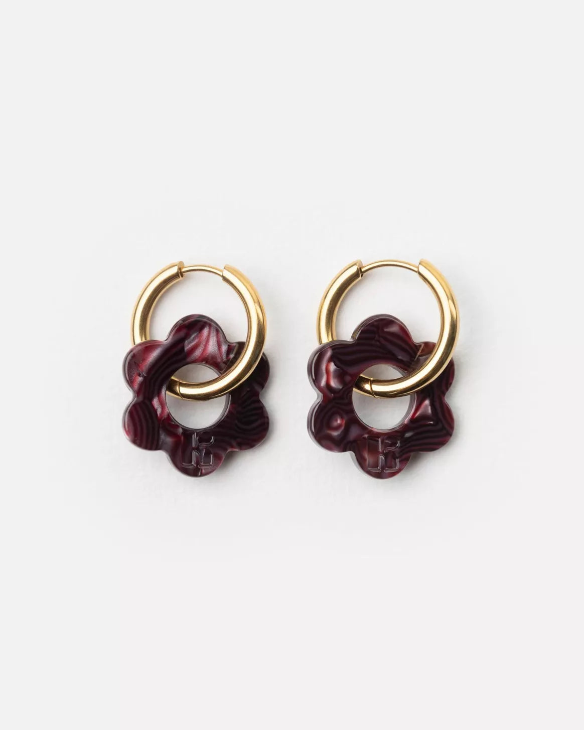 Paire de boucles d’oreilles Baby Fleurette prune de Kurage, créoles dorées avec pendentifs en forme de fleur en acétate marbré prune, présentées sur fond clair.