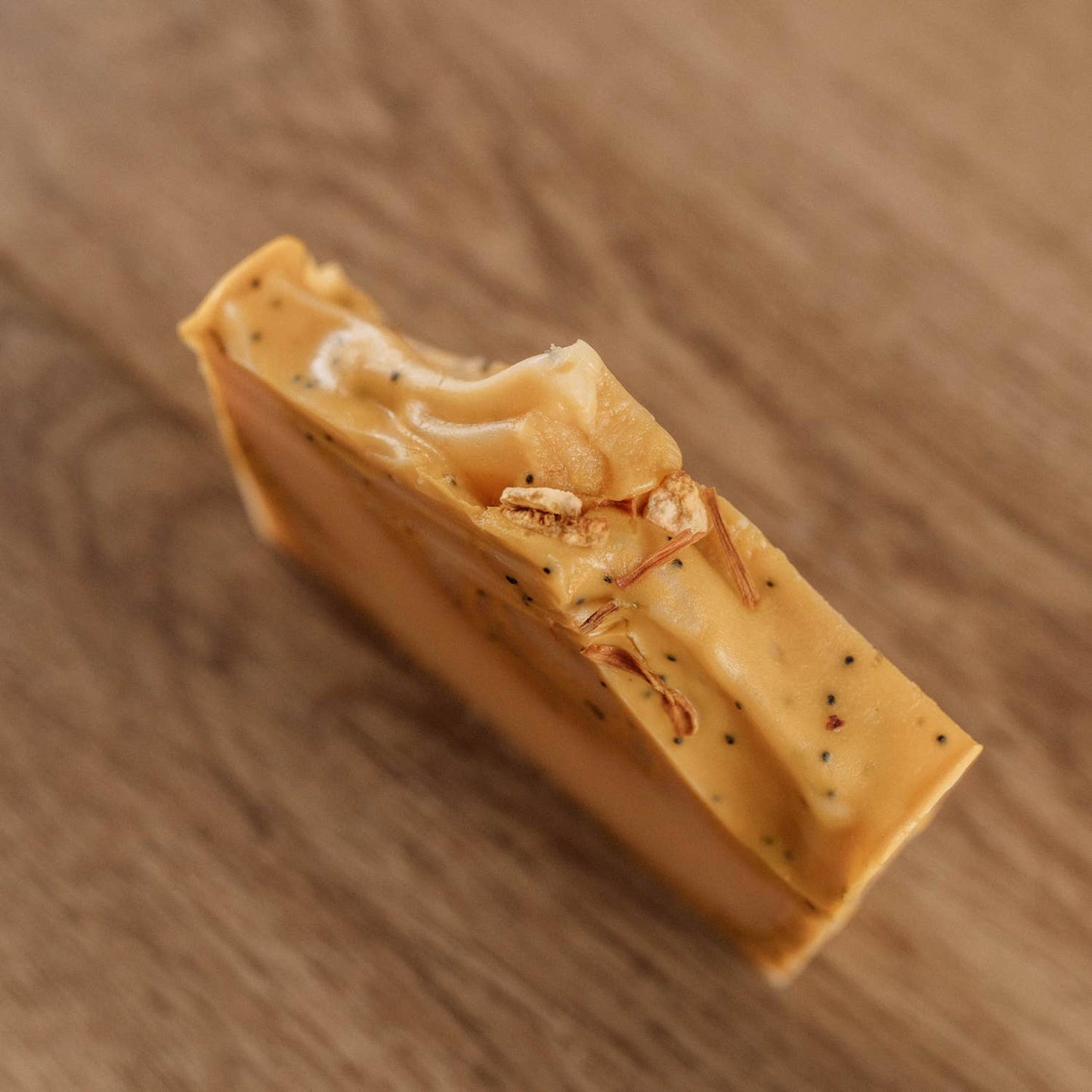 “Gros plan sur le savon Naturayl Agrumes, montrant sa texture et les graines de pavot exfoliantes sur le dessus.”