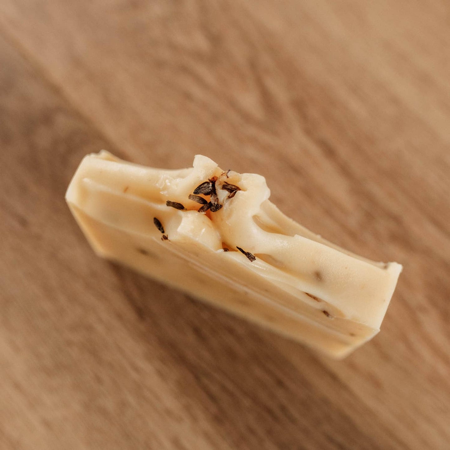 Gros plan du savon incliné, mettant en valeur sa texture et ses inclusions naturelles.