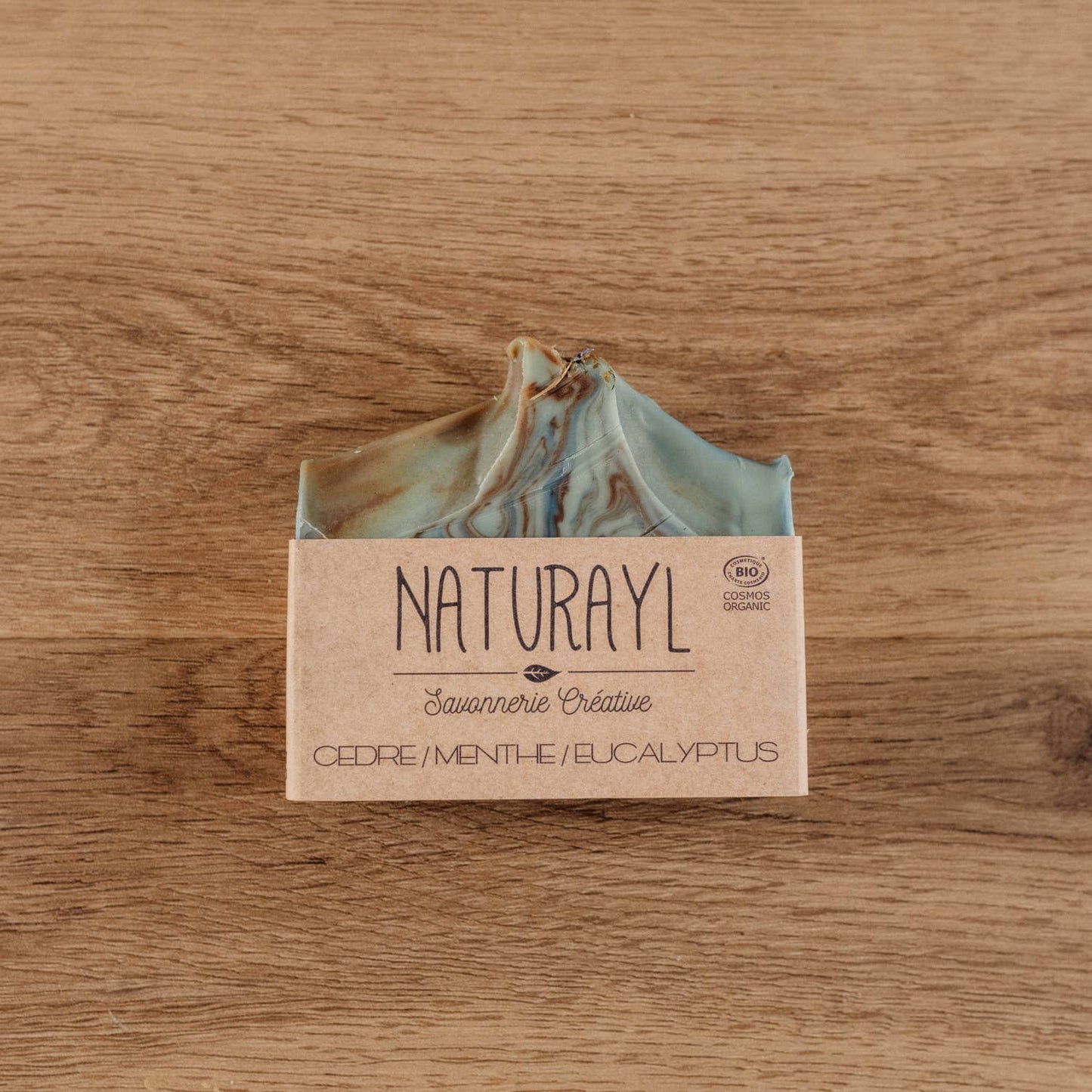 Savon Naturayl posé sur un support en bois, étiquette visible « Cèdre/Menthe/Eucalyptus »