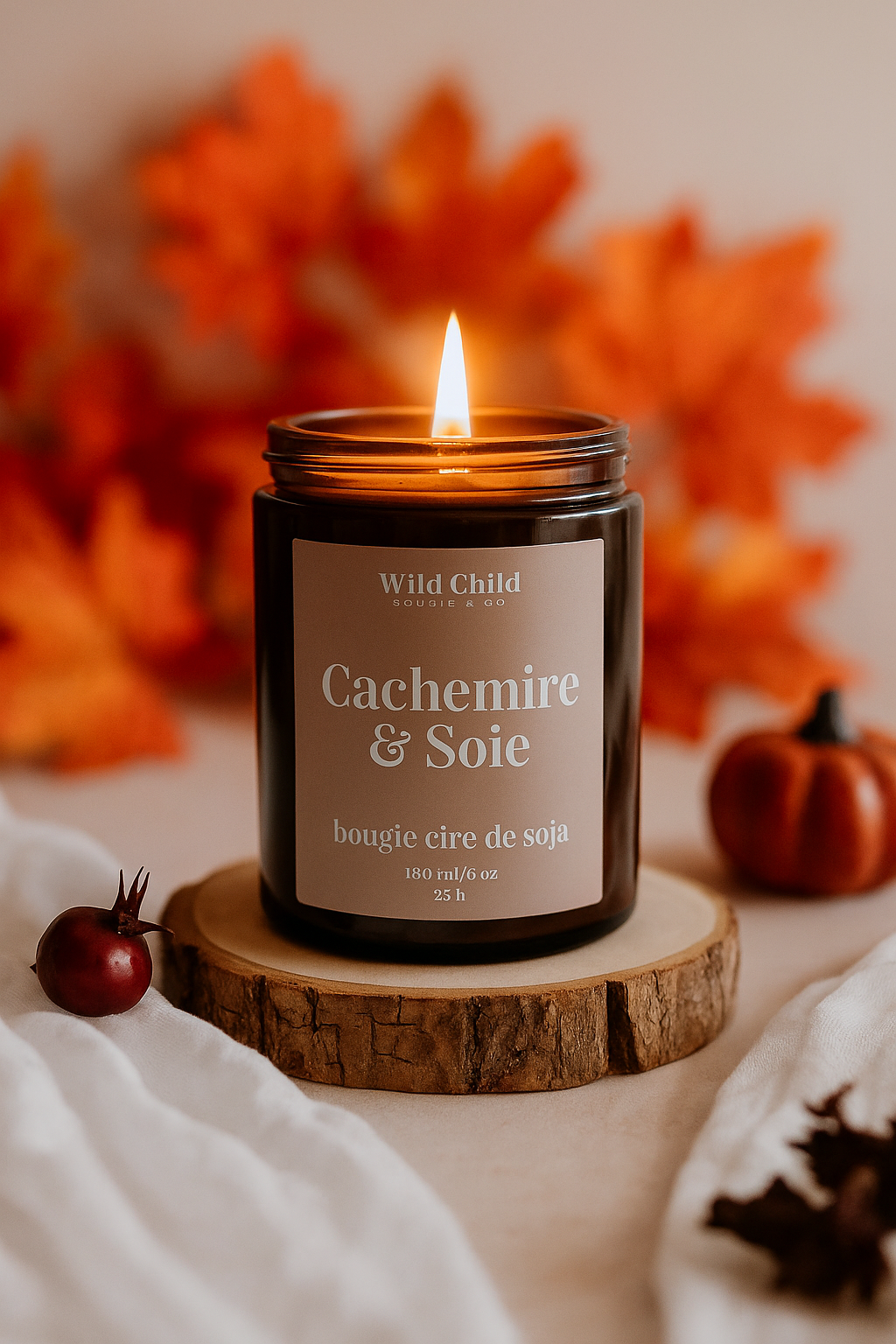 Bougie Cachemire & Soie allumée, pot ambré posé sur un rondin de bois, décor automnal orangé et ambiance cocooning.