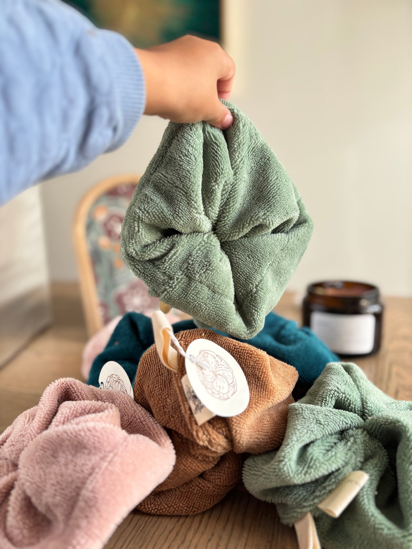 Fleur de douche lavable Marie en Août en coloris vert sauge, tenue à la main – tissu éponge douce fabriqué en France, alternative zéro déchet pour la douche.