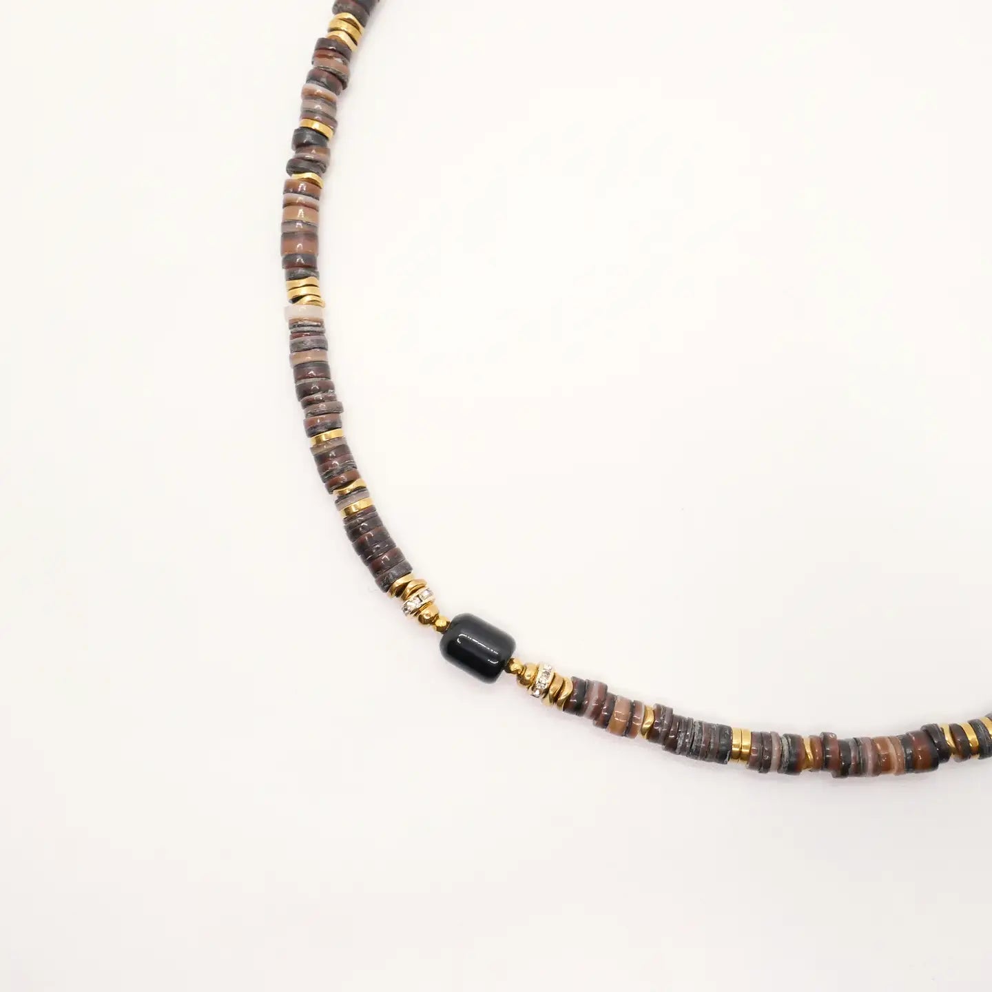 Détail du collier Lonnie avec perles Heishi marron, rondelles dorées et pierre centrale noire sur fond blanc.