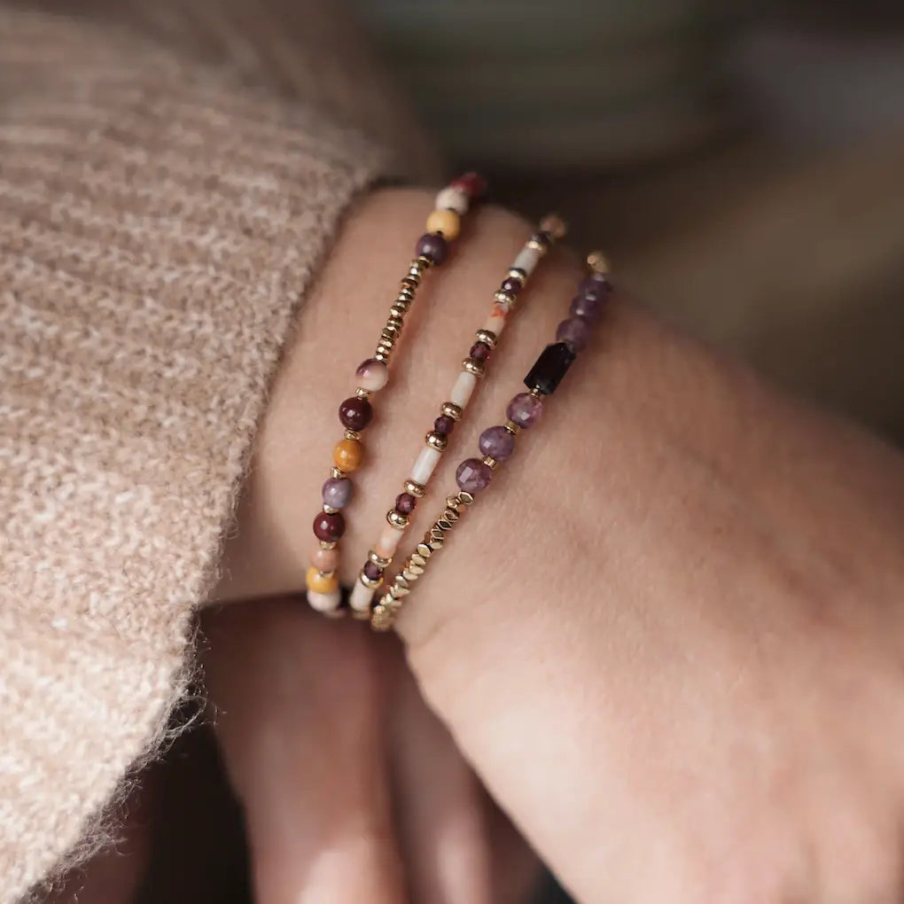 Bracelet Zélie porté au poignet, associé à d’autres bracelets aux tons violets et dorés pour un effet d’accumulation élégant.