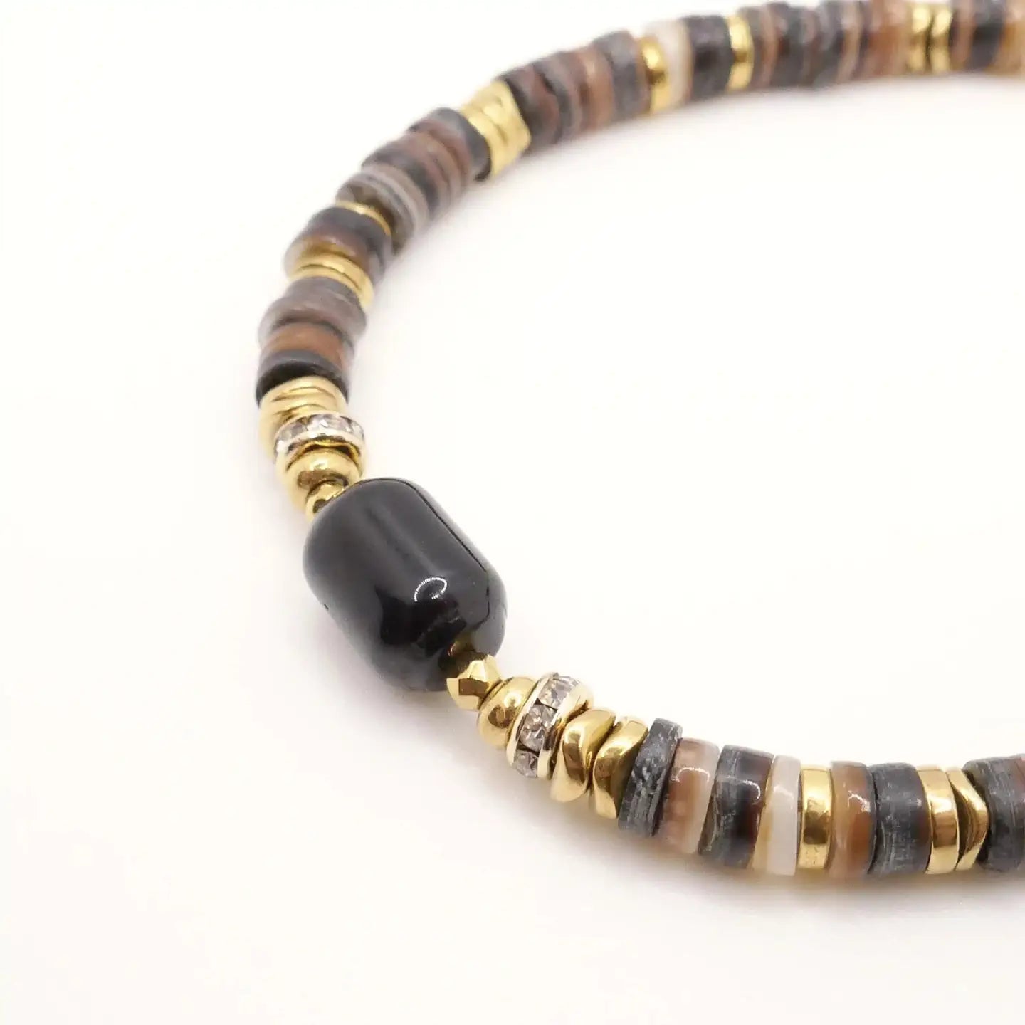 Zoom sur le bracelet Hermine composé de perles Heishi marrons, perles dorées et pierre centrale noire, présenté en détail sur fond blanc
