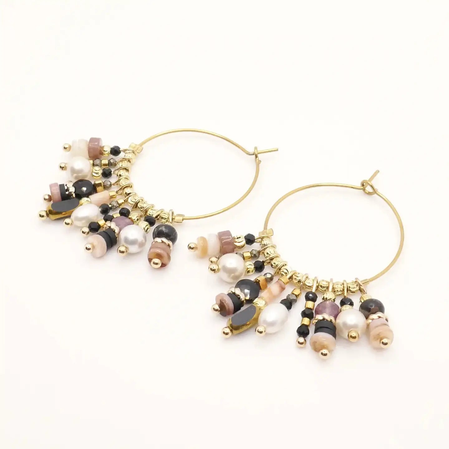 Boucles d’oreilles créoles Grace noires en gros plan, décorées de perles naturelles et éléments dorés.