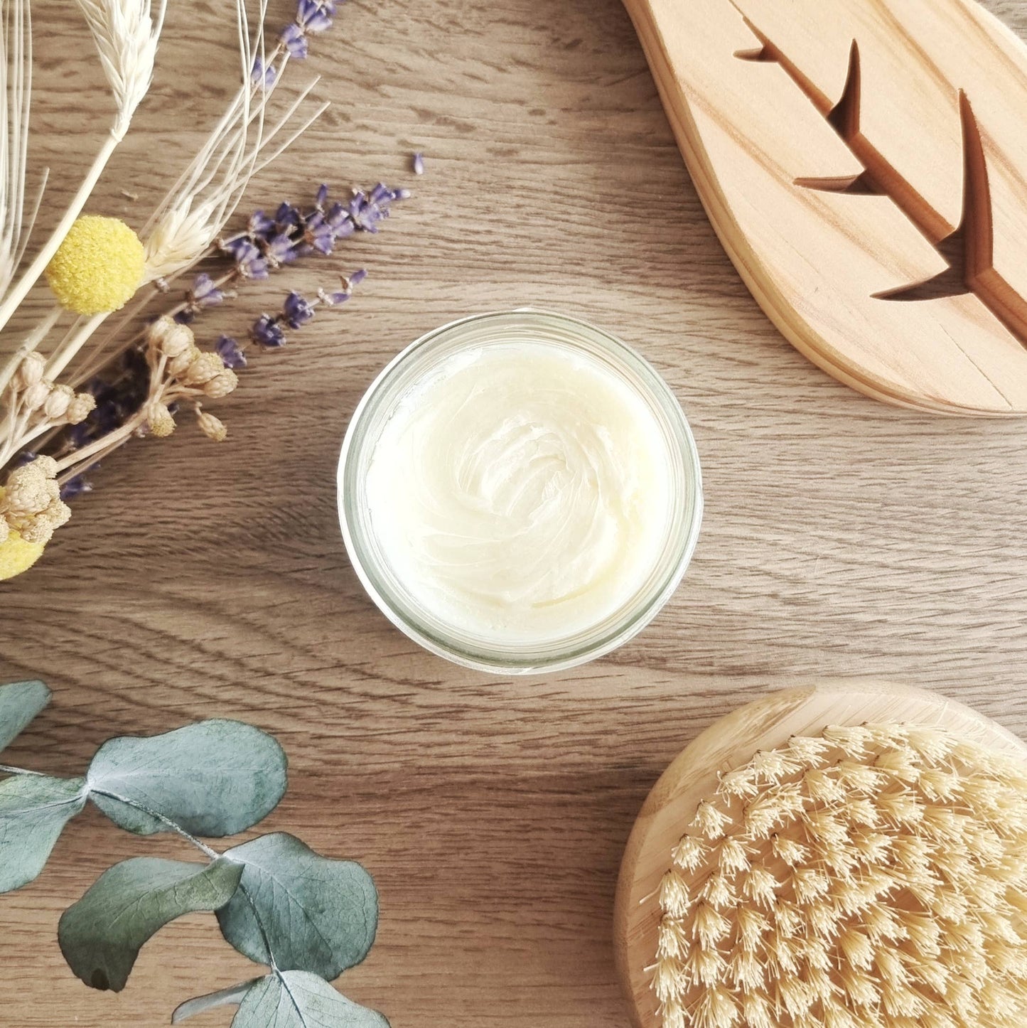 Ouverture du pot avec la texture fondante visible, accompagnée d’accessoires de soin (brosse naturelle).