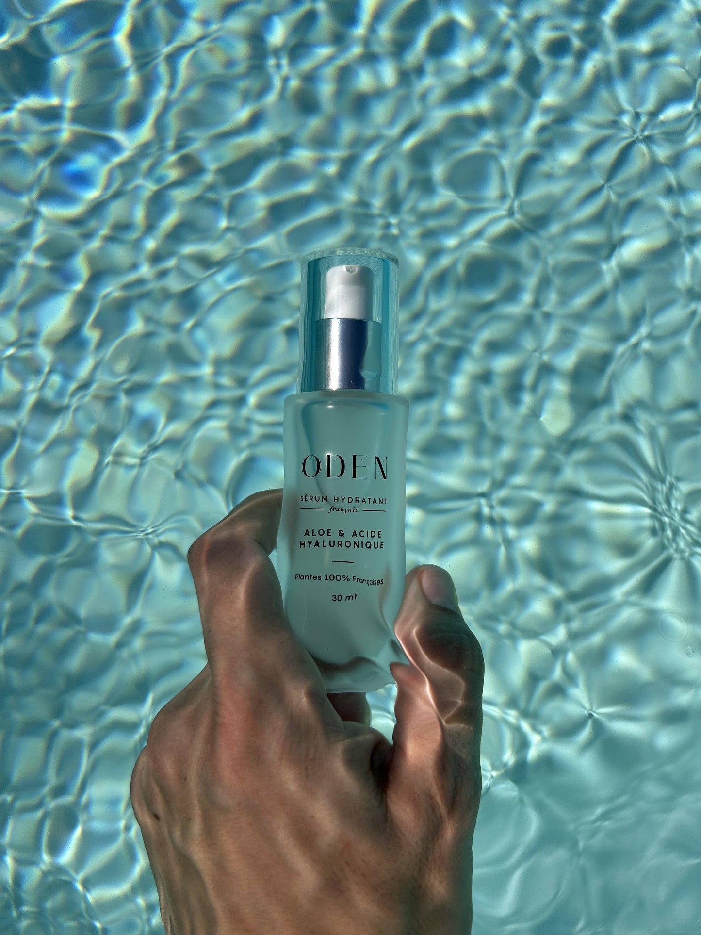 Flacon de sérum Oden au bord d’une piscine, ambiance fraîcheur et pureté