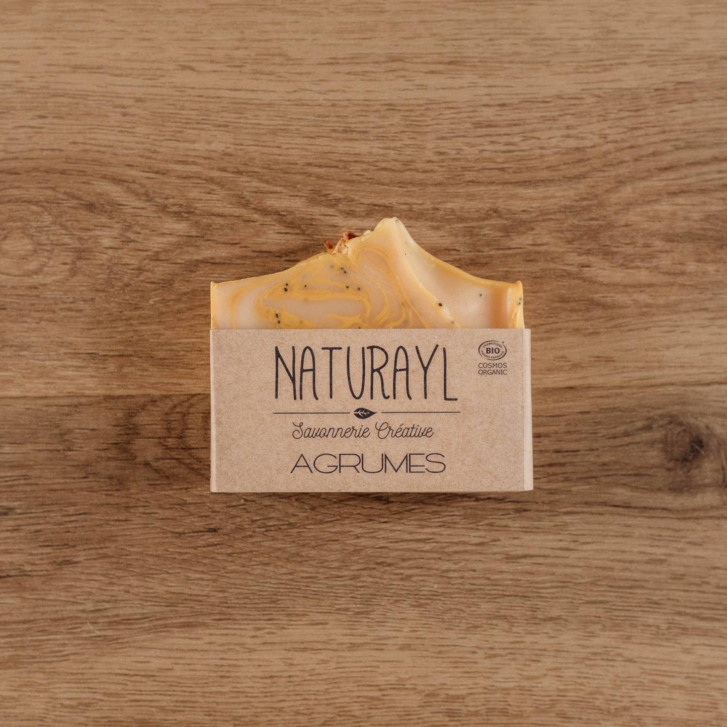 “Savon solide Naturayl parfum Agrumes posé sur une surface en bois, avec son emballage kraft artisanal.”